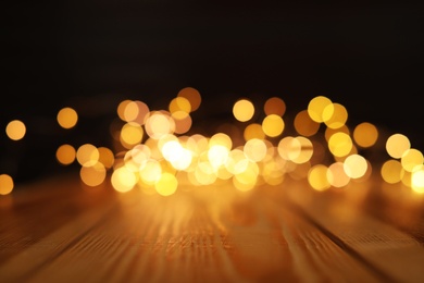 Photo of Empty wooden surface and blurred lights on background. Bokeh effect