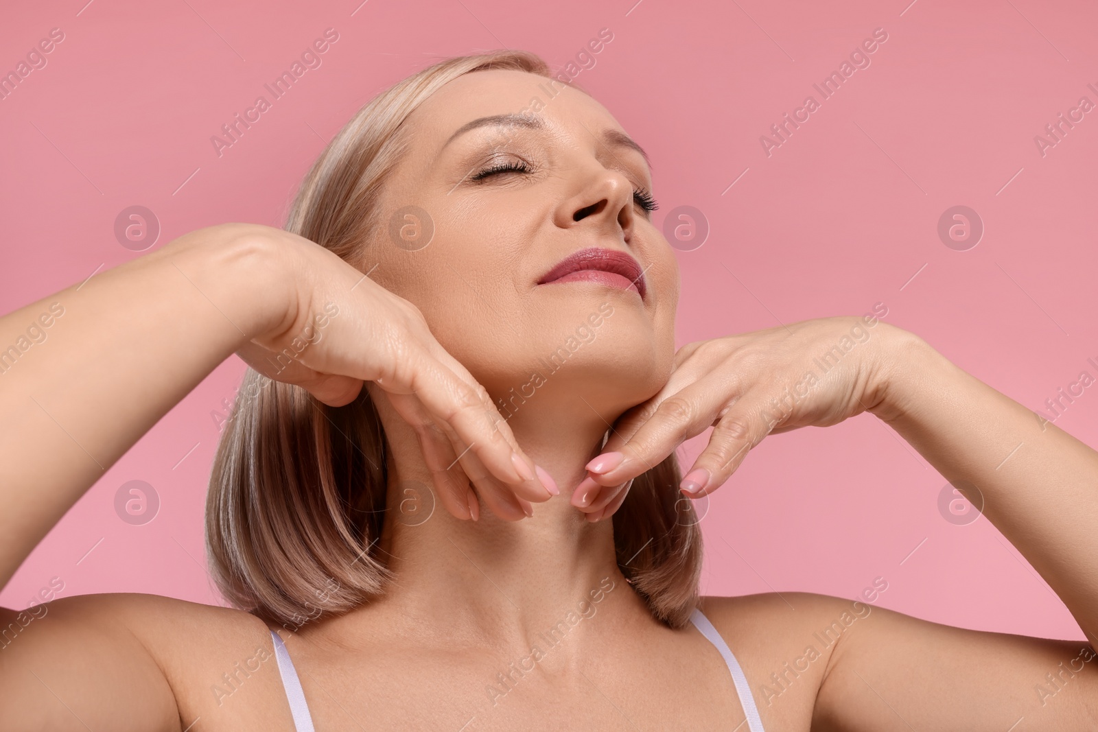 Photo of Beautiful woman touching her neck on pink background