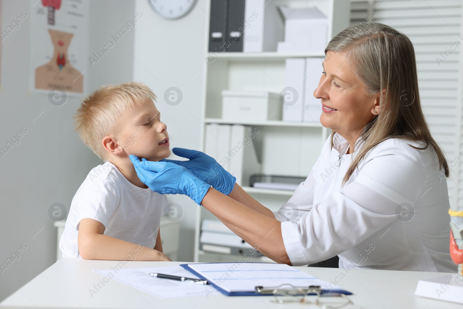 Photo of Endocrinologist examining boy's thyroid gland at table in hospital