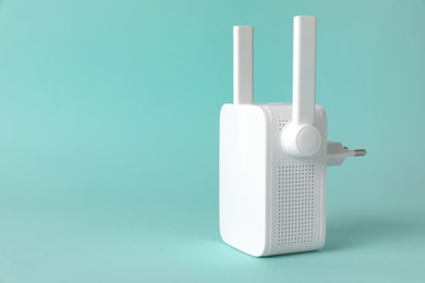 Photo of New modern Wi-Fi repeater on turquoise background, space for text