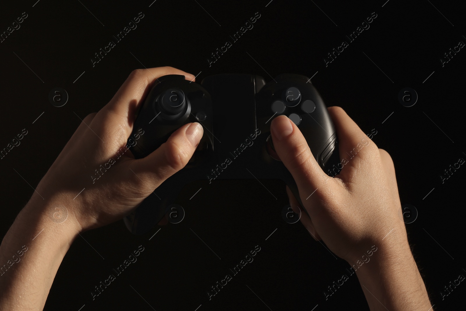 Photo of Woman holding video game controller on black background, closeup