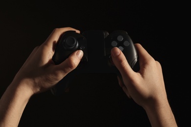 Photo of Woman holding video game controller on black background, closeup