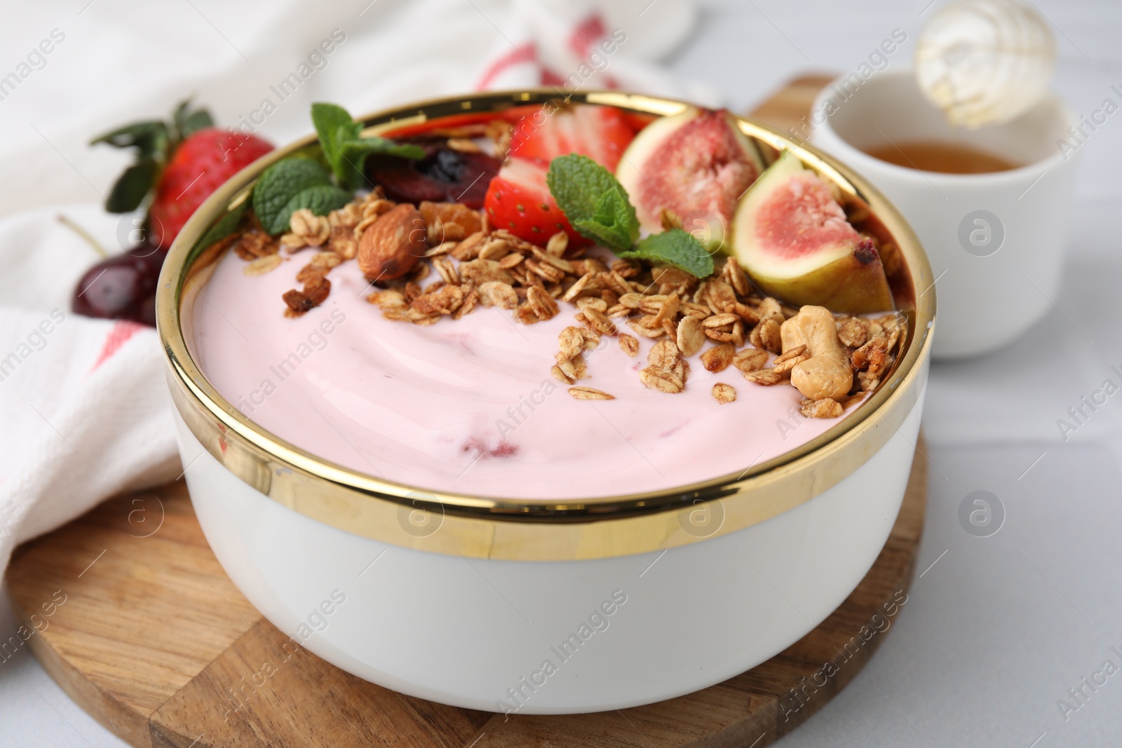 Photo of Bowl with yogurt, fruits and granola on white table, closeup