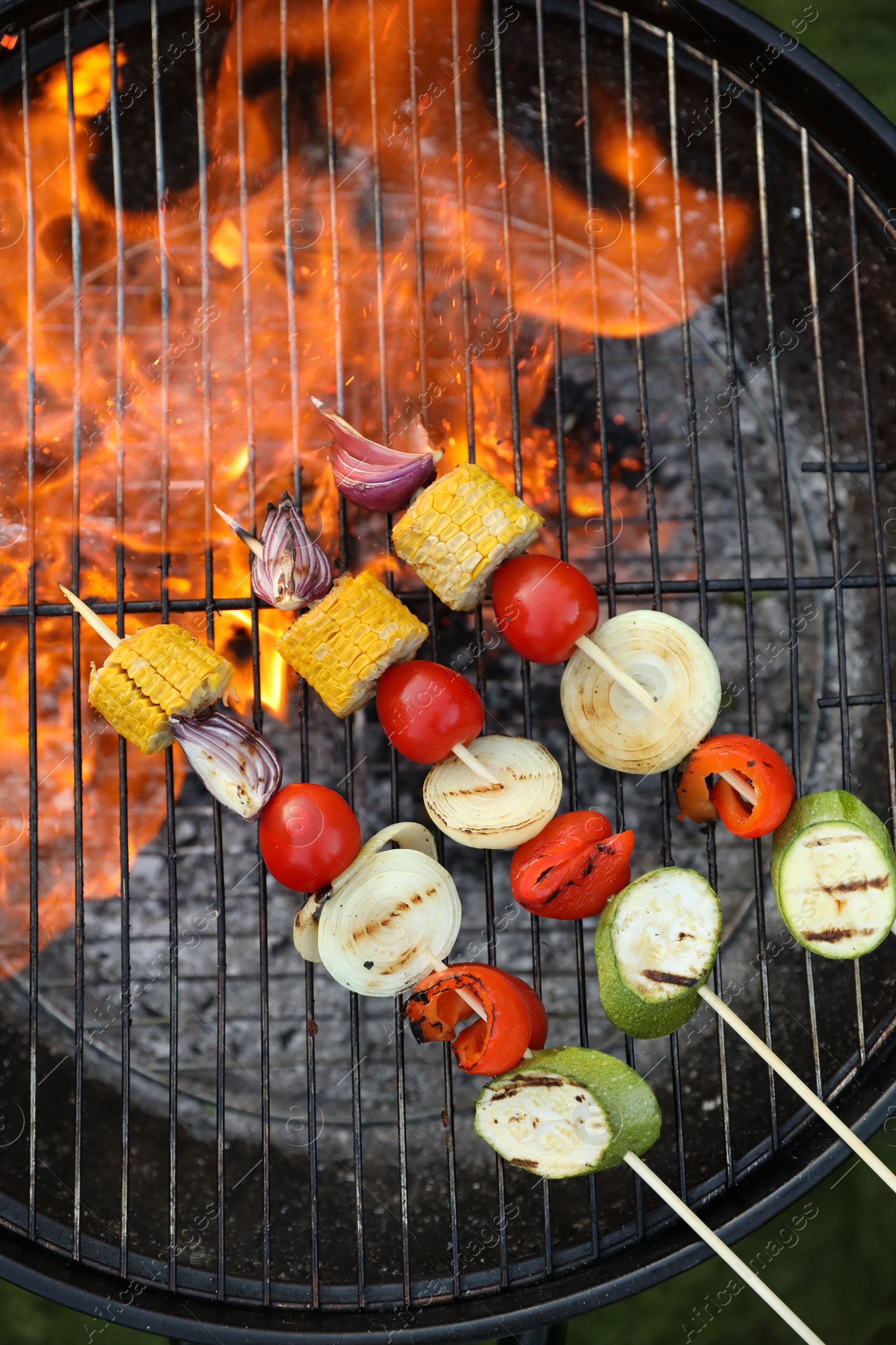 Photo of Skewers with delicious grilled vegetables on barbecue grill outdoors, top view
