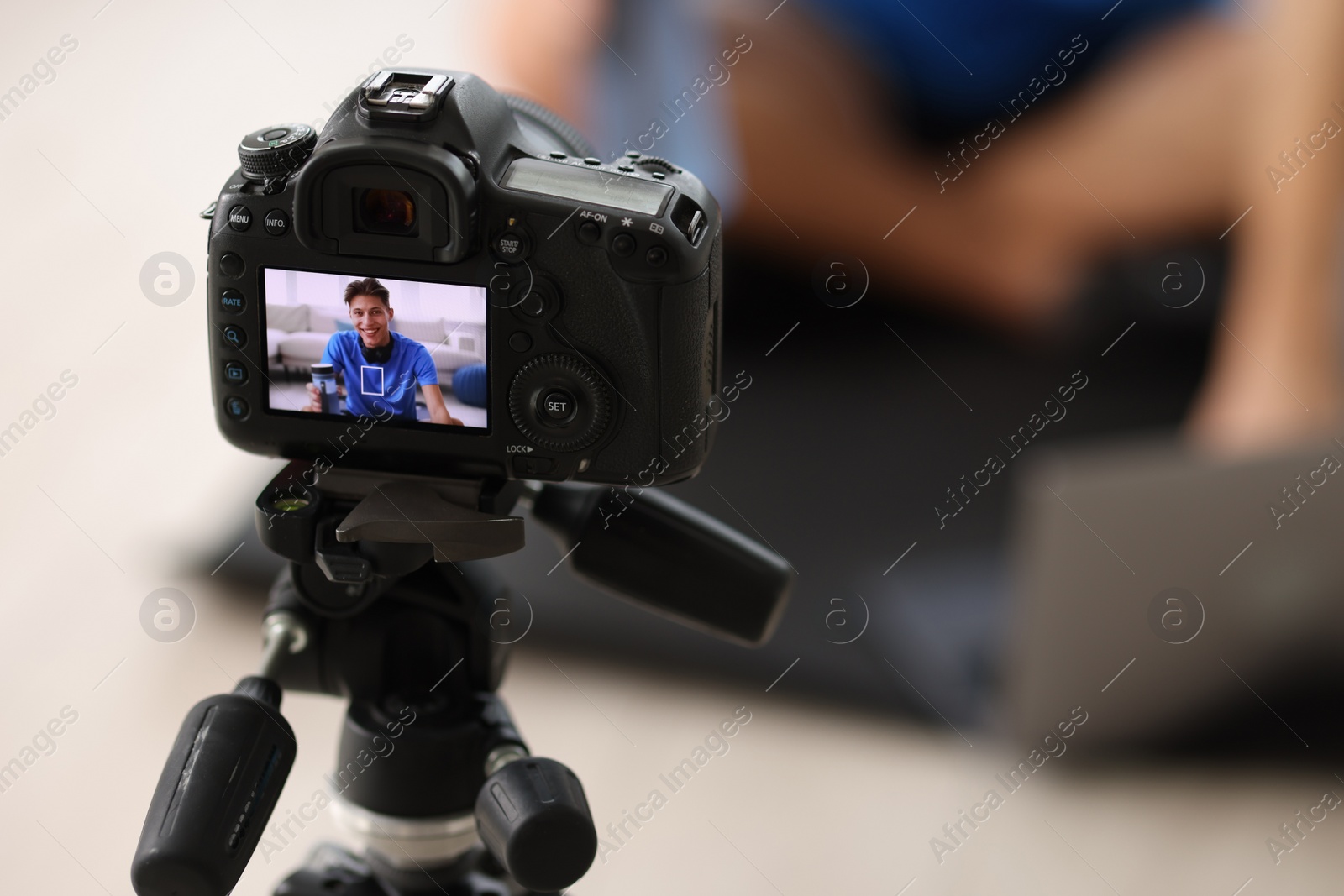 Photo of Smiling sports blogger recording fitness lesson at home, focus on camera. Space for text