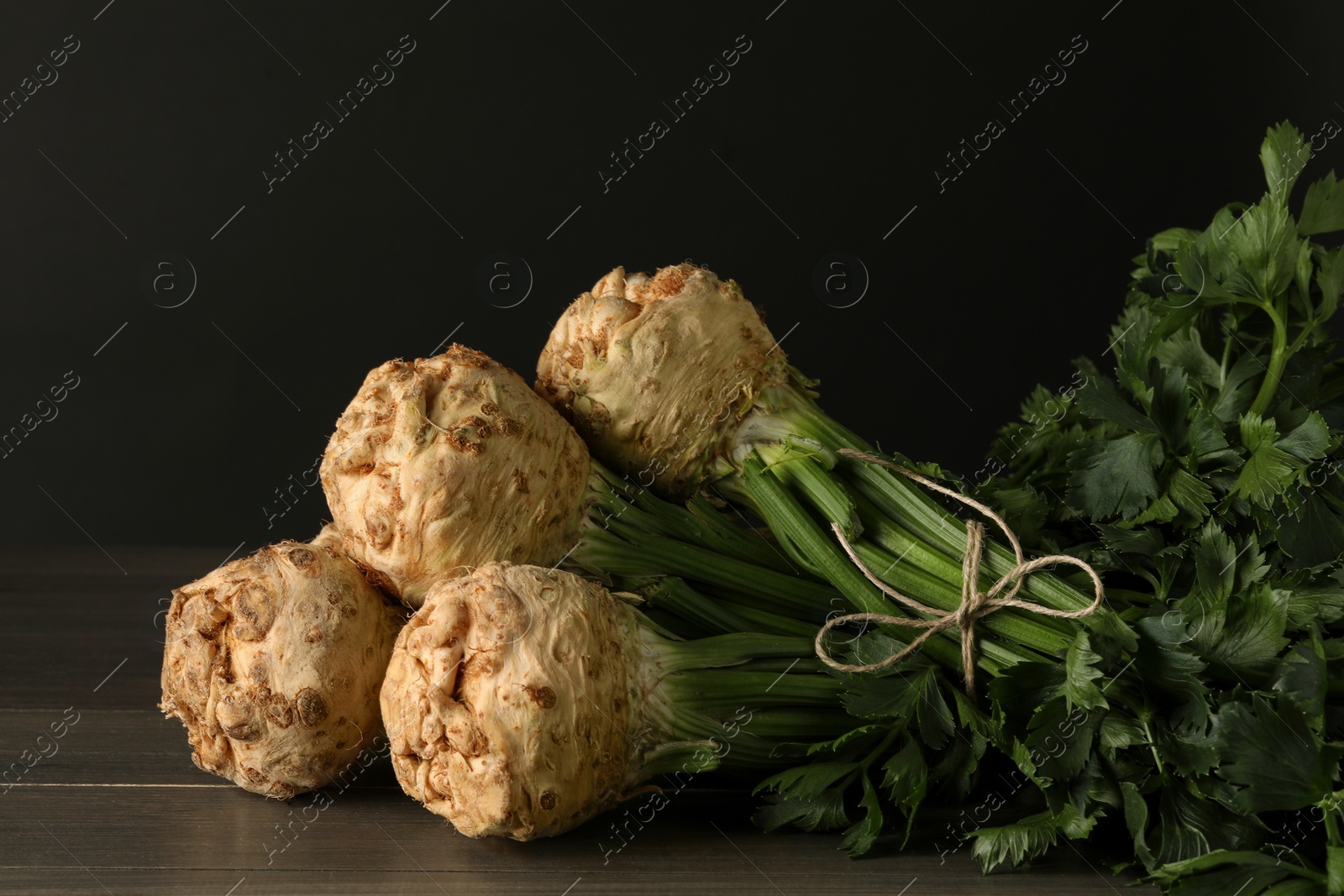 Photo of Fresh raw celery roots on wooden table, closeup. Space for text