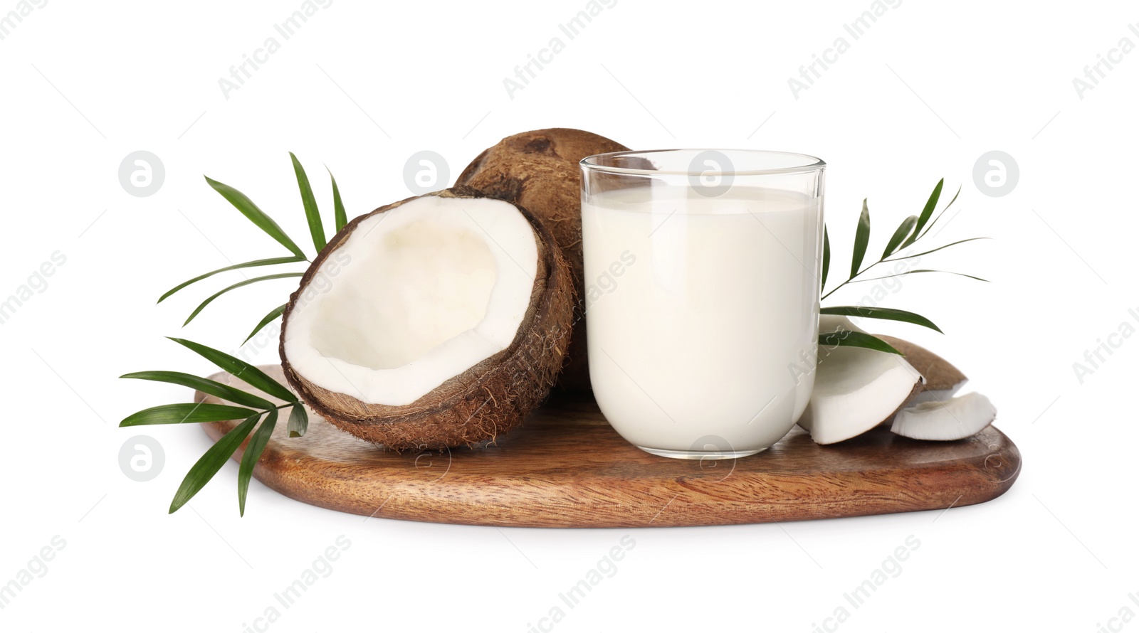 Photo of Glass of delicious vegan milk, coconuts and green leaves on white background