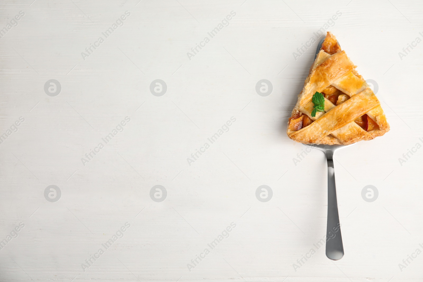Photo of Slice of delicious fresh peach pie on white wooden table, top view. Space for text