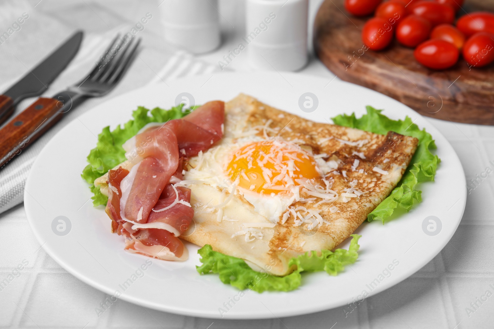 Photo of Delicious crepe with egg served on white tiled table. Breton galette