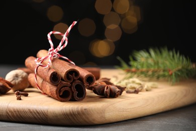 Photo of Cinnamon sticks and other spices on table against black background with blurred lights, closeup