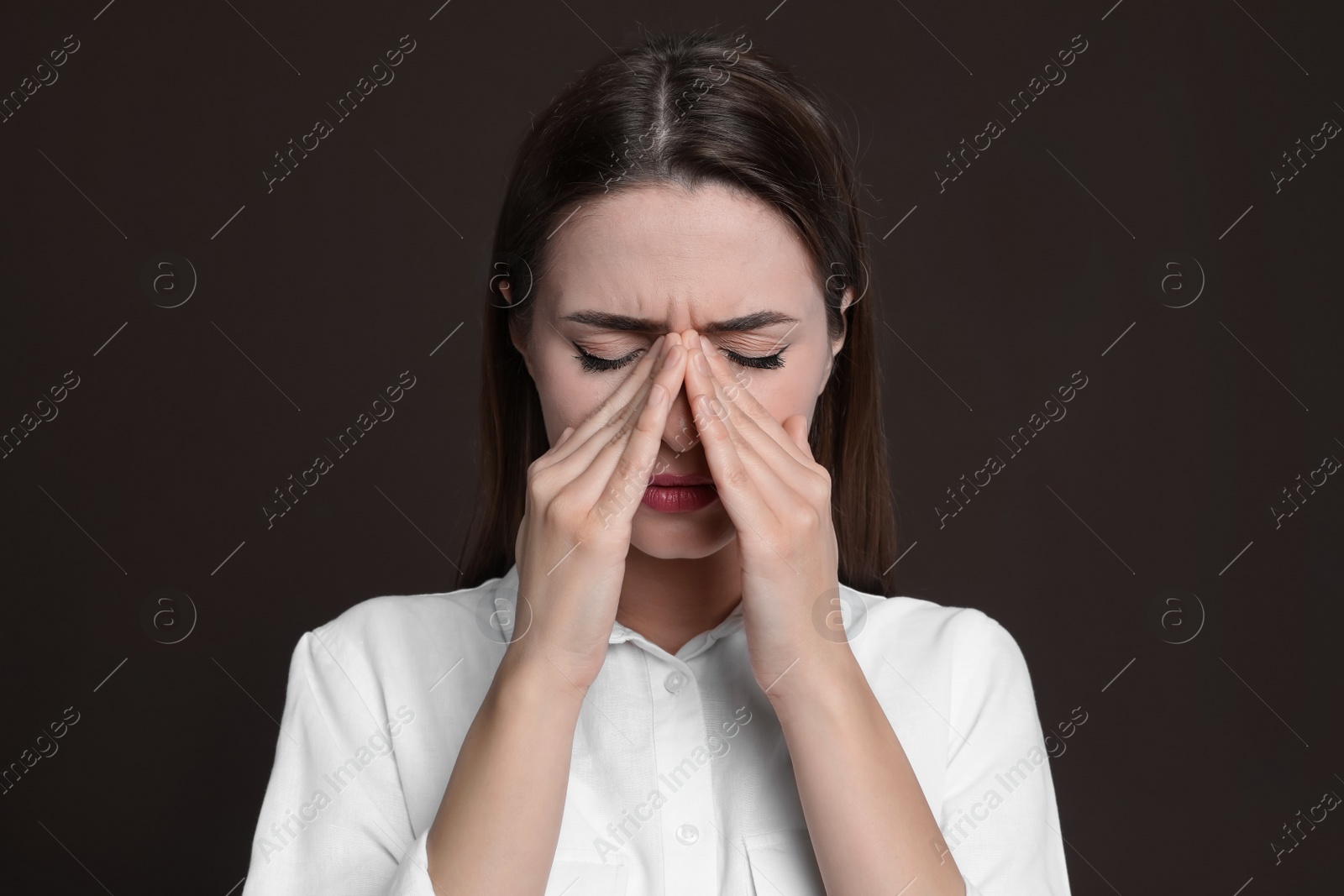 Photo of Young woman suffering from headache on brown background