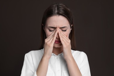 Young woman suffering from headache on brown background