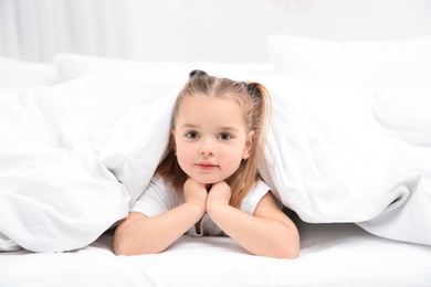 Photo of Beautiful little girl in bed at home. Bedtime schedule