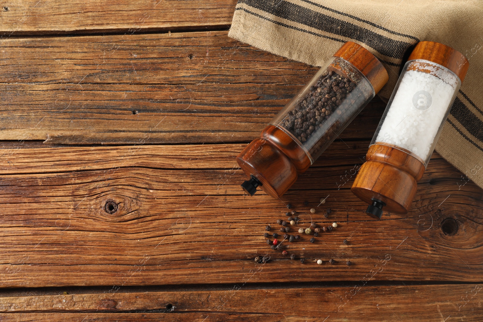 Photo of Salt and pepper shakers on wooden table, flat lay. Space for text