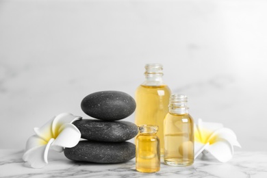 Beautiful composition with aroma oil and spa stones  on white marble table