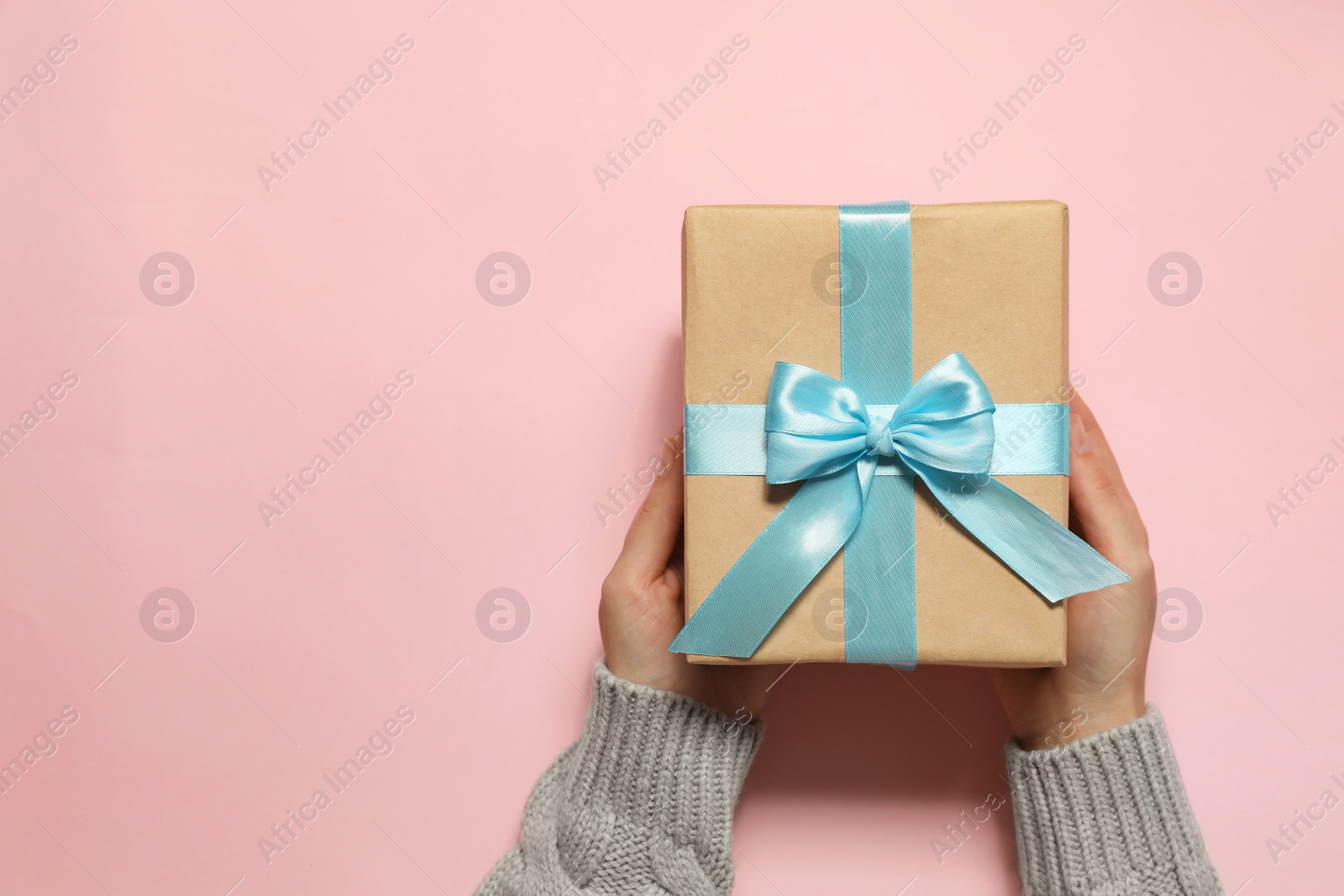 Photo of Woman holding Christmas gift on pink background, top view. Space for text