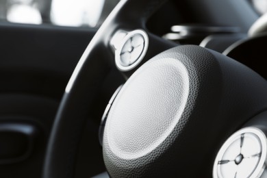 Black steering wheel inside of modern car, closeup