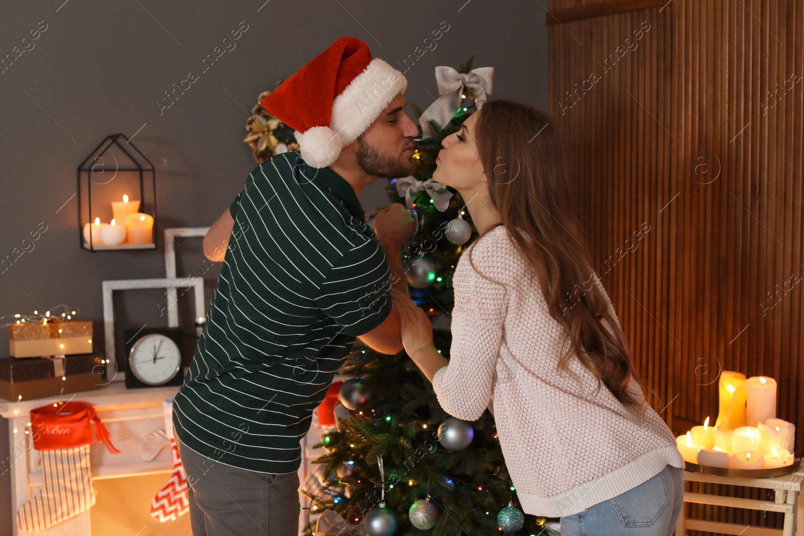 Photo of Happy young couple decorating Christmas tree together at home