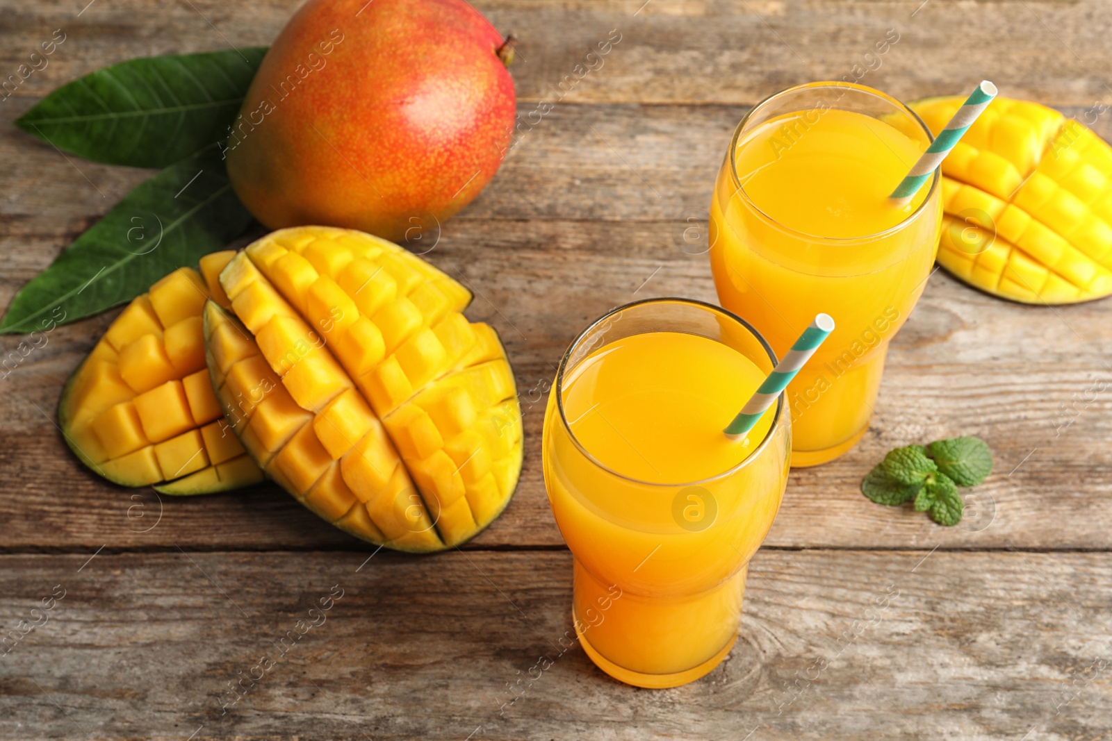 Photo of Fresh tropical mango juice and fruits on wooden table