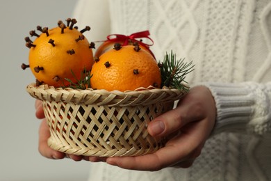 Woman with pomander balls made of fresh tangerines and cloves on light background, closeup