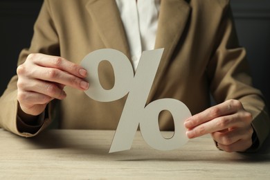 Photo of Woman holding percent sign at wooden table, closeup