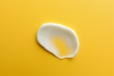 Photo of Sample of face cream on yellow background, top view