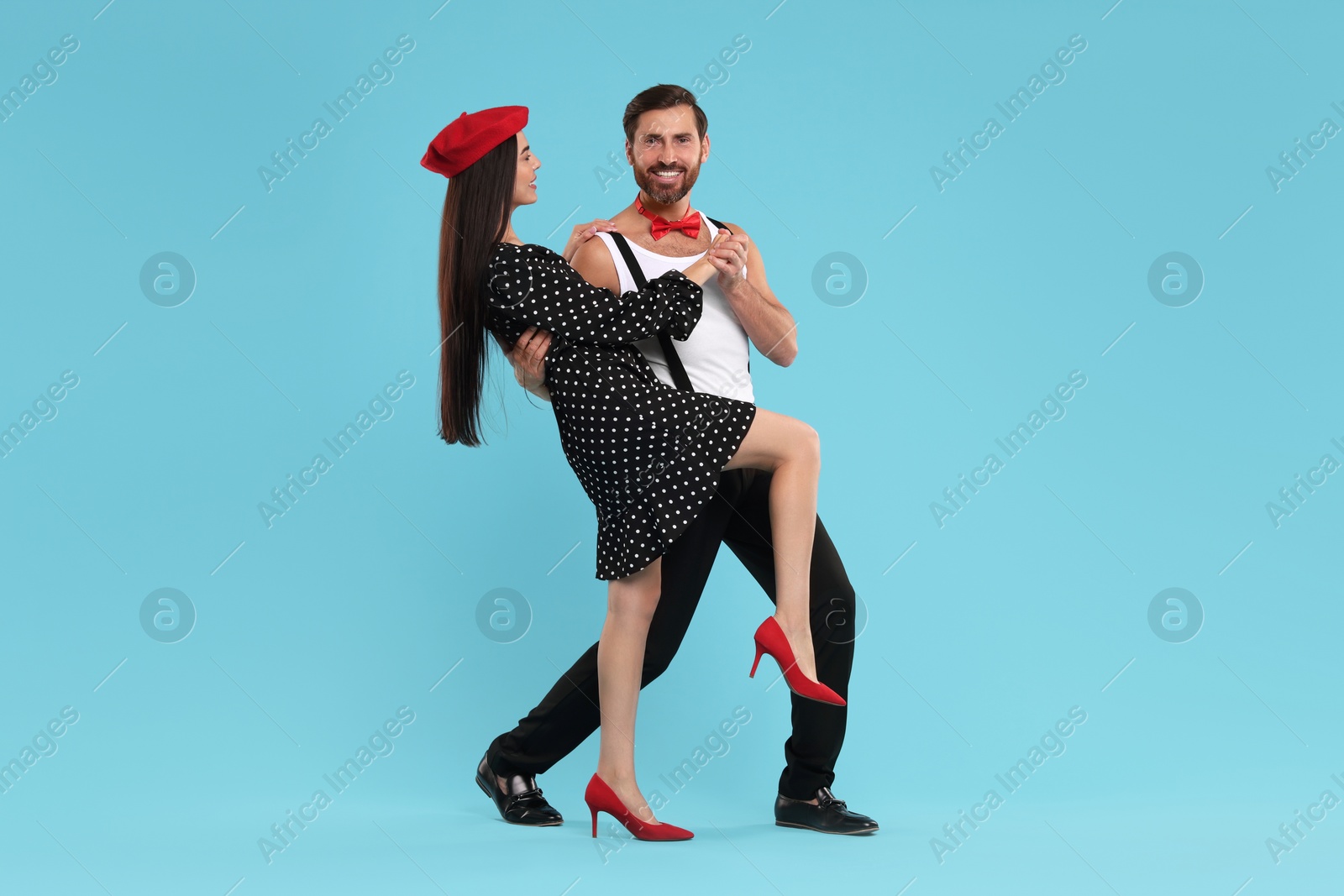 Photo of Happy couple dancing together on light blue background