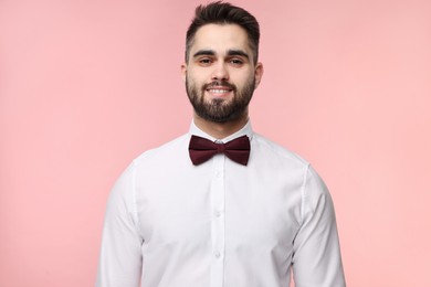 Photo of Portrait of smiling man in shirt and bow tie on pink background