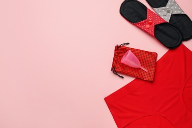 Photo of Women's underwear, reusable cloth pads and menstrual cup on pink background, flat lay. Space for text