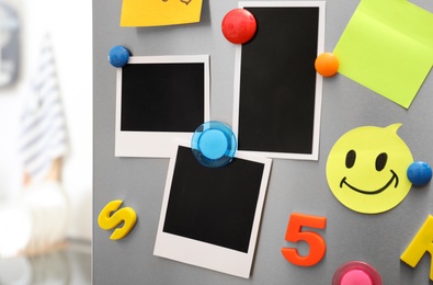 Sheets of paper and photos with colorful magnets on refrigerator door in kitchen. Space for text