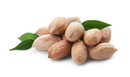 Heap of pecan nuts in shell and leaves on white background