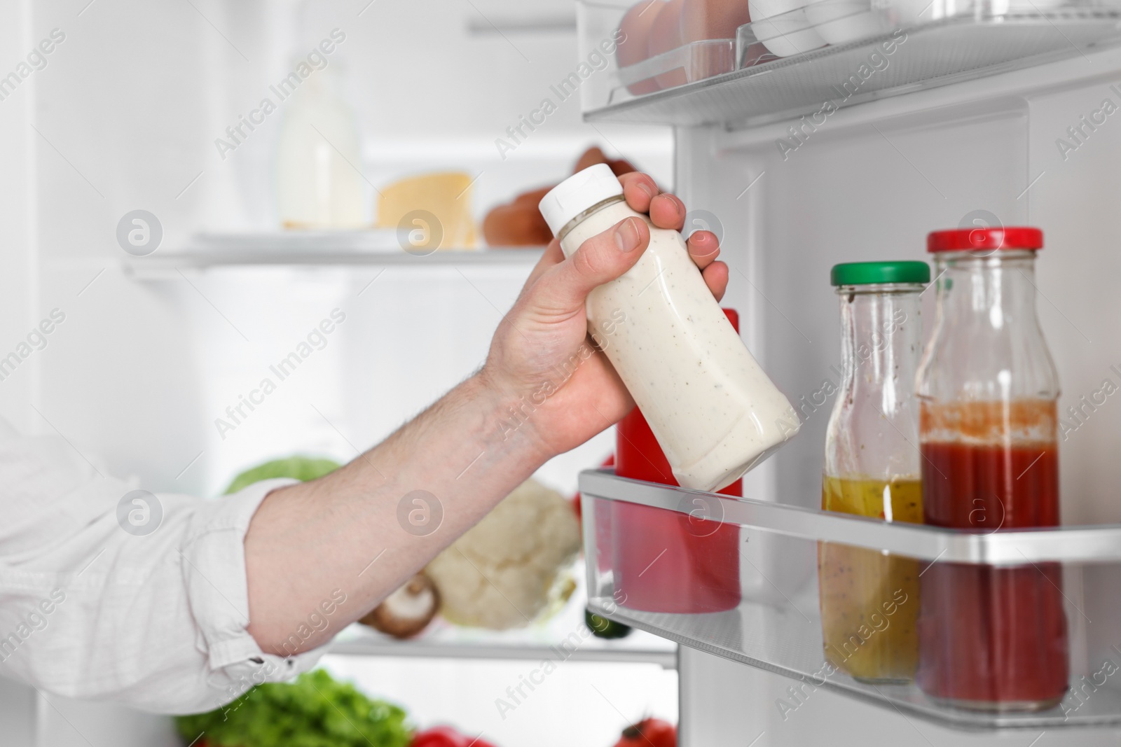 Photo of Man taking sauce out of refrigerator, closeup