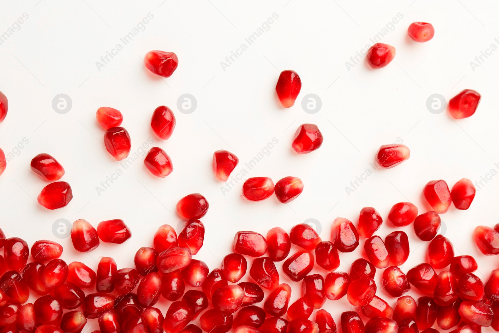 Photo of Many ripe juicy pomegranate grains on white background, flat lay