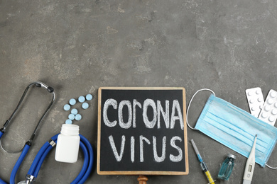 Chalkboard with words CORONA VIRUS, stethoscope and medicines on grey stone background, flat lay. Space for text