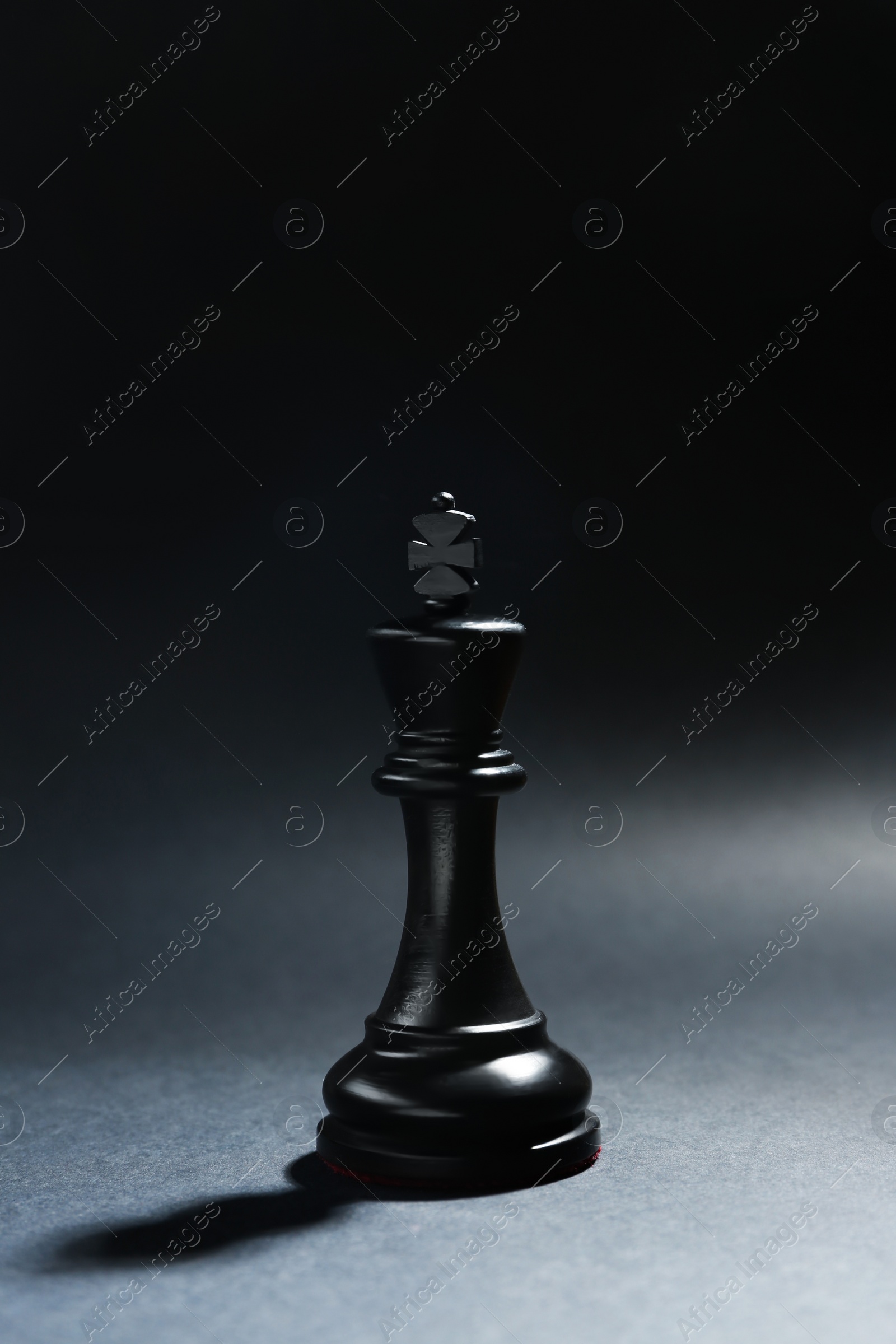 Photo of Black wooden chess king on dark background