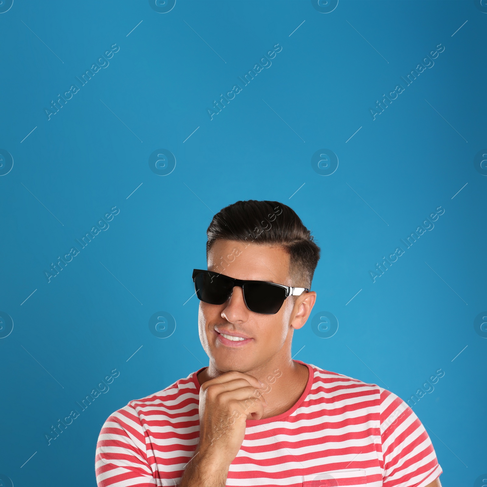 Photo of Handsome man wearing sunglasses on blue background