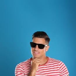 Handsome man wearing sunglasses on blue background