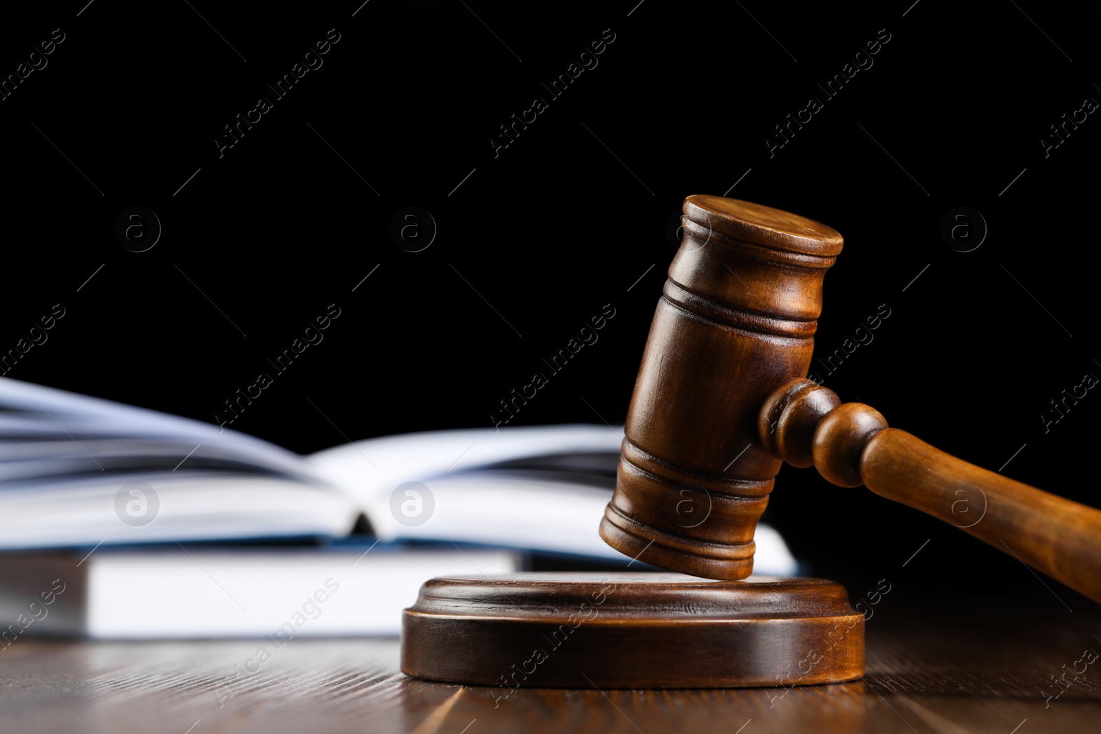 Photo of Wooden gavel and books on table against blurred background, closeup. Space for text