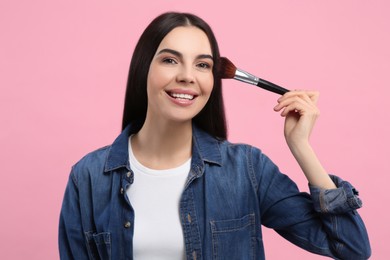 Photo of Beautiful woman with makeup brush on pink background