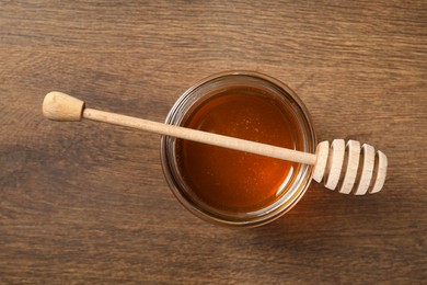 Photo of Dipper and jar with honey on wooden table, top view