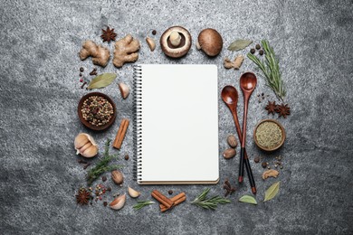 Open recipe book and different ingredients on grey table, flat lay. Space for text