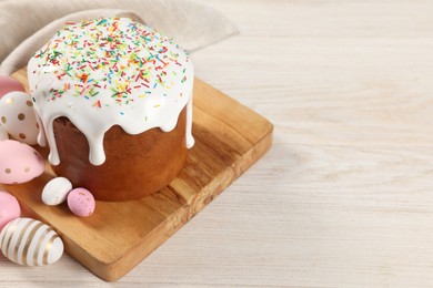 Delicious Easter cake with sprinkles and decorated eggs on white wooden table. Space for text