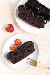Photo of Pieces of chocolate sponge cake and strawberries on beige textured table, flat lay