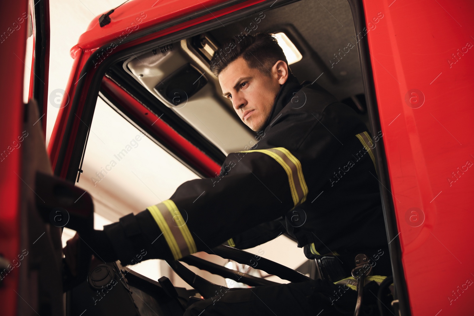 Photo of Firefighter sitting in fire truck at station, low angle view