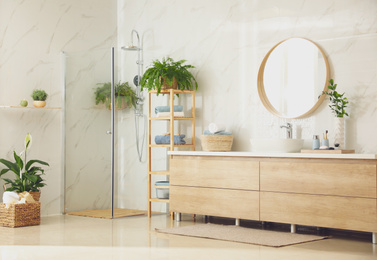 Stylish bathroom interior with countertop, shower stall and houseplants. Design idea