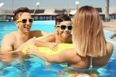 Happy family in swimming pool on sunny day outdoors