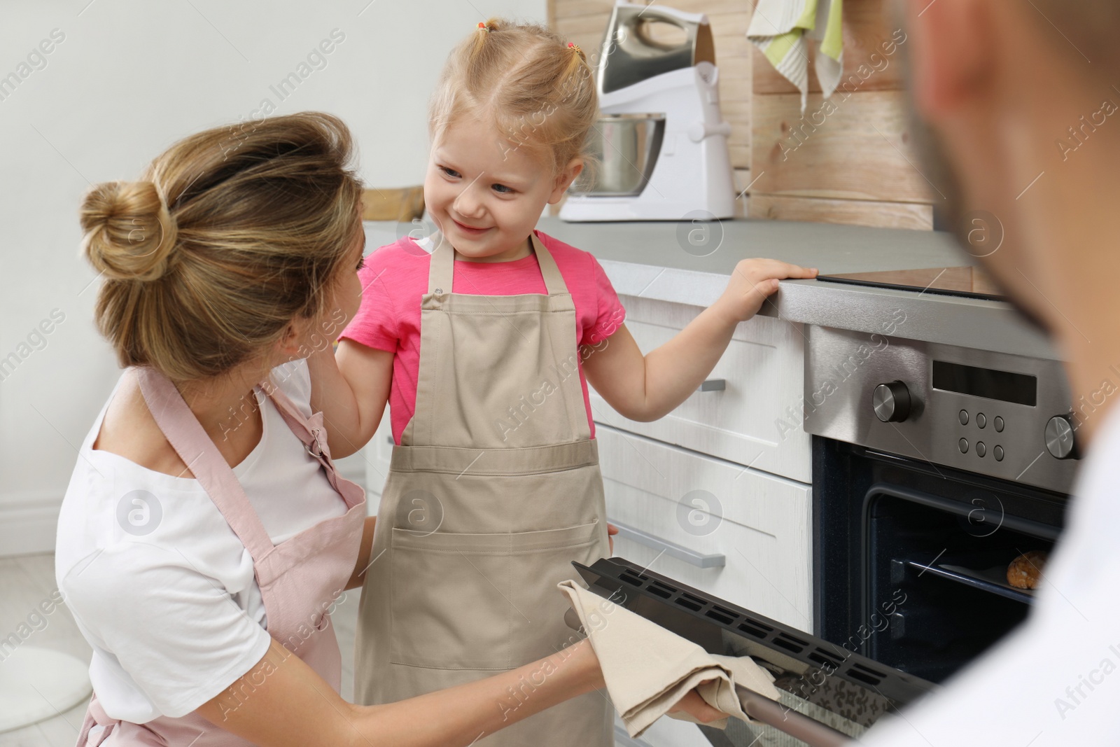 Photo of Happy family baking cookies in oven at home