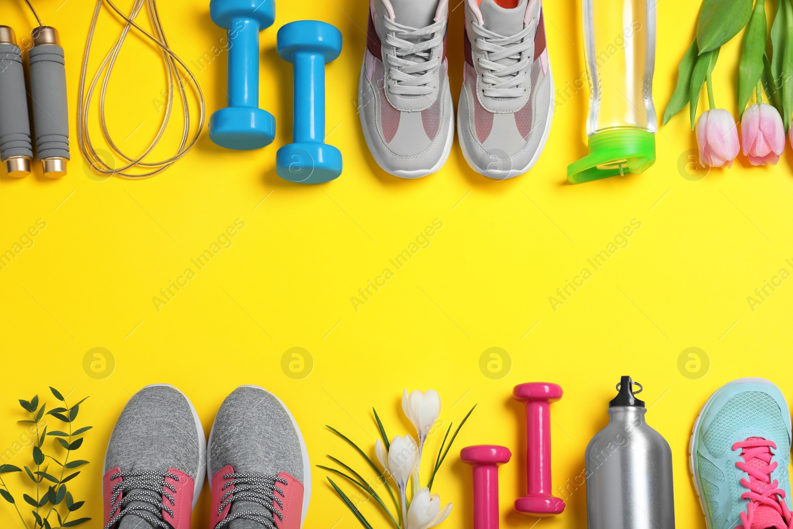 Photo of Frame made with spring flowers and sports items on yellow background, flat lay. Space for text