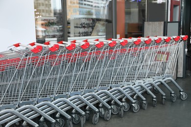 Row of empty metal shopping carts near supermarket outdoors