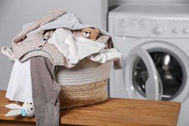 Photo of Laundry basket with baby clothes and toys on table in bathroom. Space for text